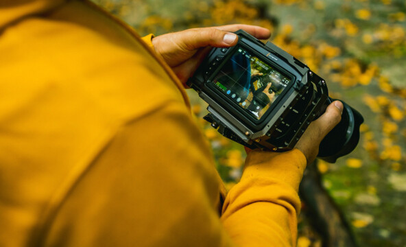 En ung person håller i en kamera i naturen.