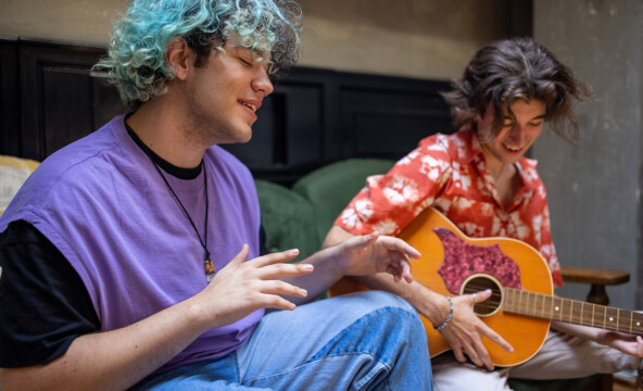 En blåhårig tonåring sjunger och en annan i hawaiiskjorta spelar gitarr.