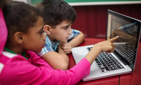 En flicka och pojke använder datorn tillsammans.