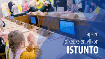 Lapsia istuu ison, virallisen näköisen pöydän ääressä.