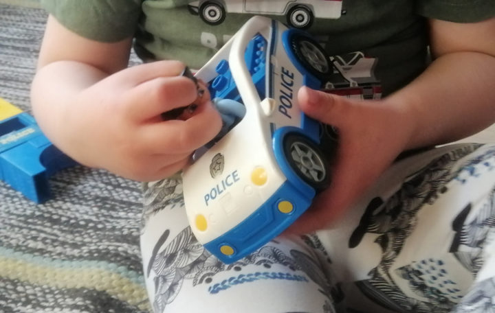 Ett barn leker med en polisbil. 